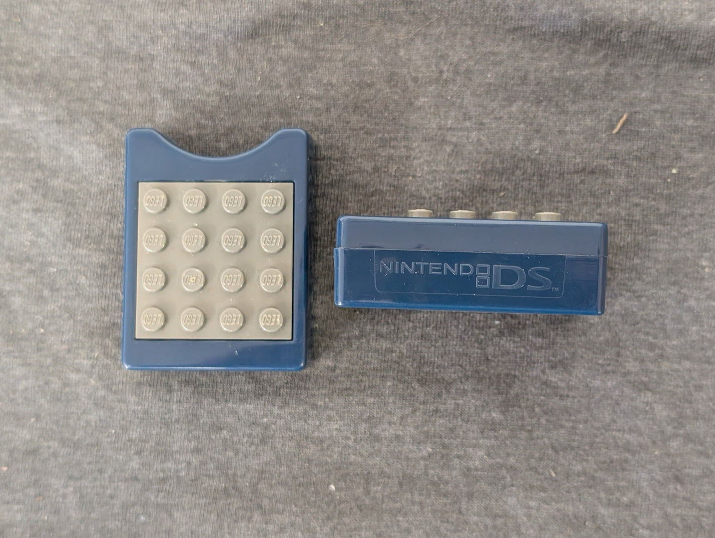 Two blue Nintendo DS game holders, one showing Lego studs on the back