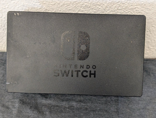Front view of a heavily scratched black Nintendo Switch dock