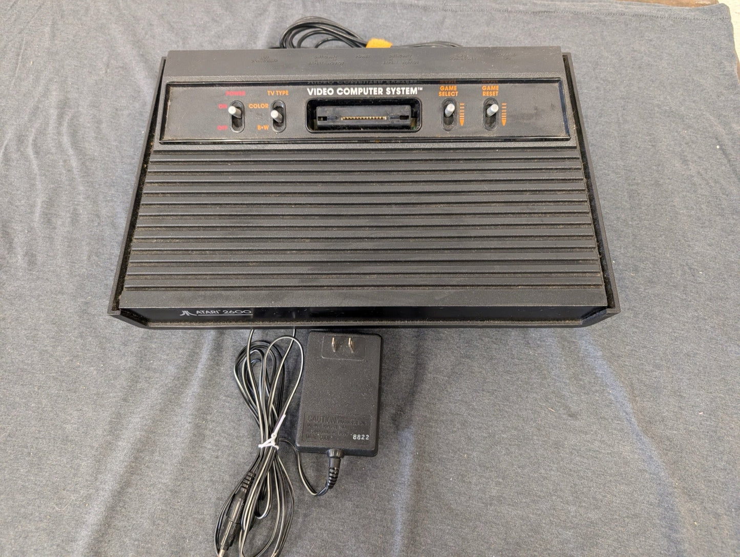 Black Atari 2600 4-switch console with power adapter.