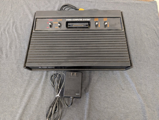 Black Atari 2600 4-switch console with power adapter.