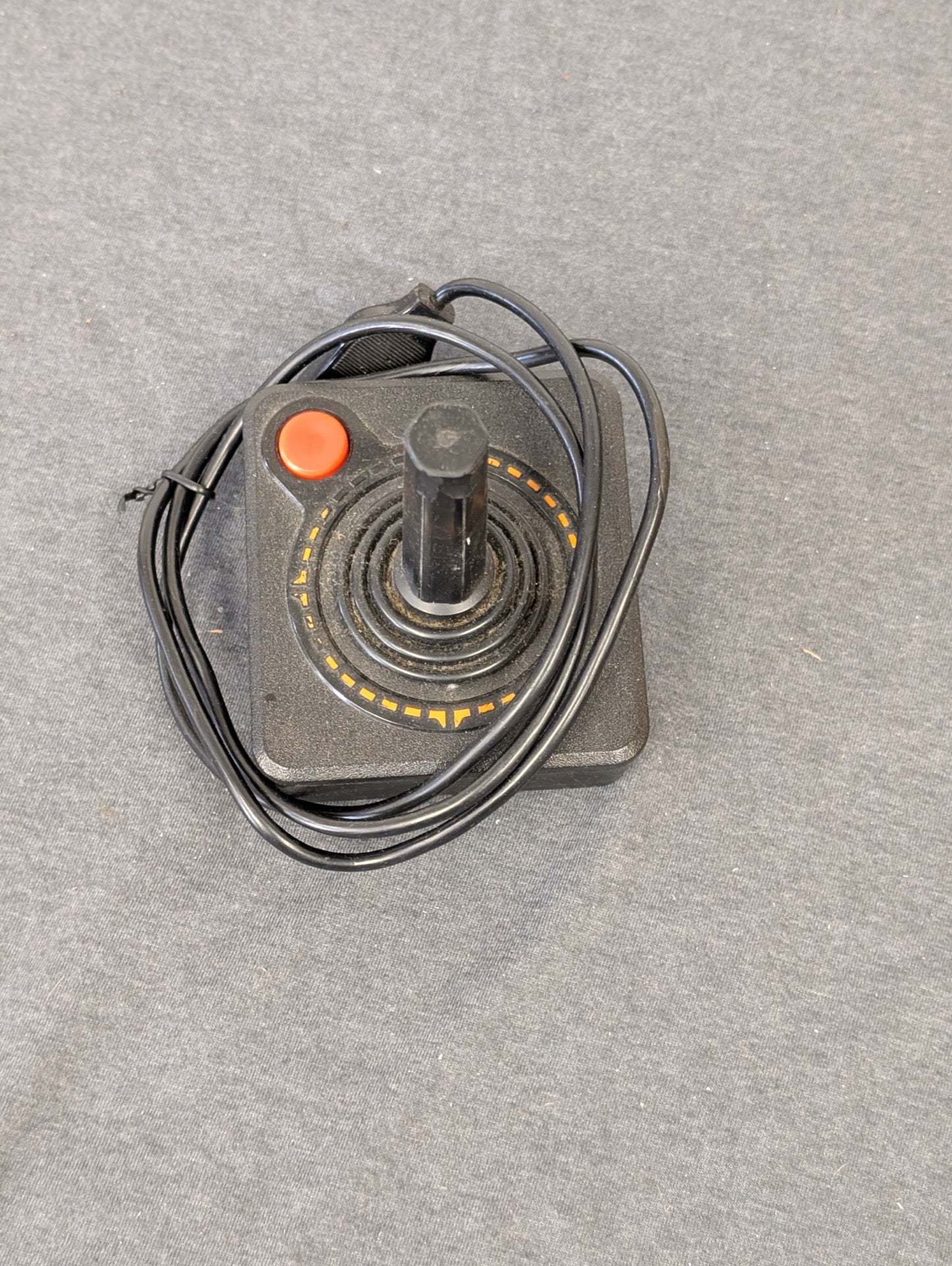 Single black Atari CX40 joystick with orange directional ring.