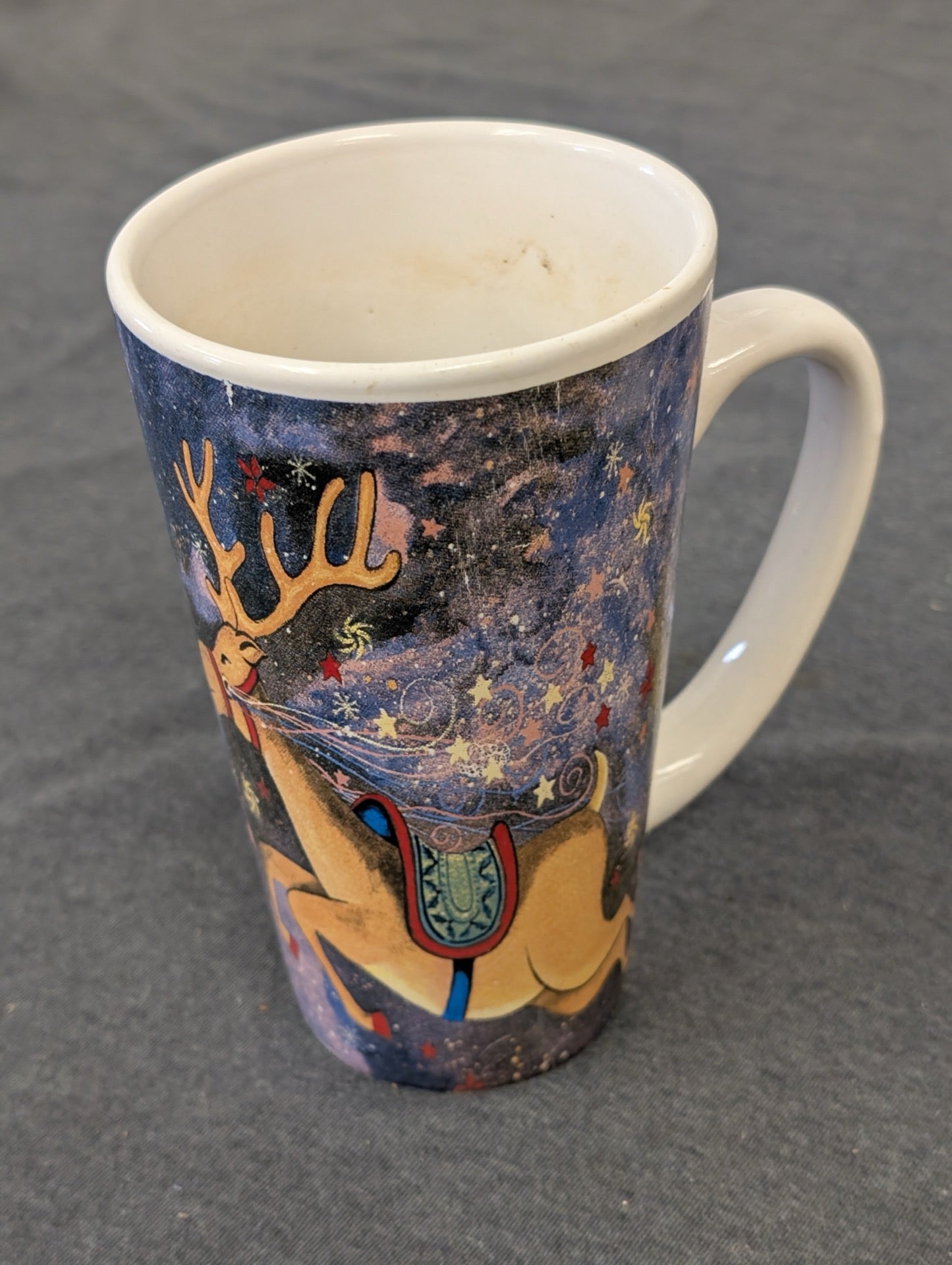 Tall ceramic coffee mug featuring a flying reindeer on a starry night background.