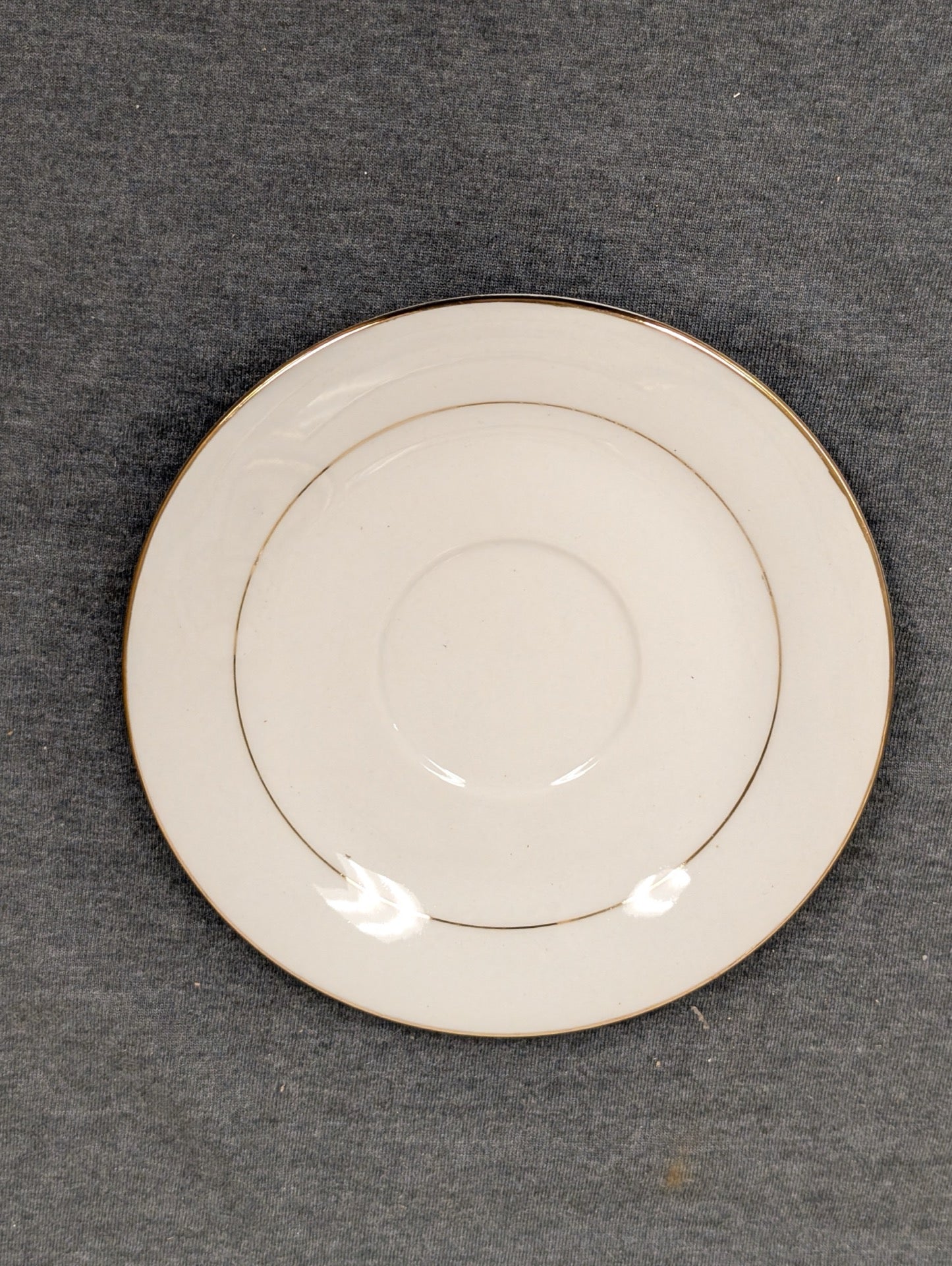 Front view of a small Sakura Classic Gold saucer plate with center indent.