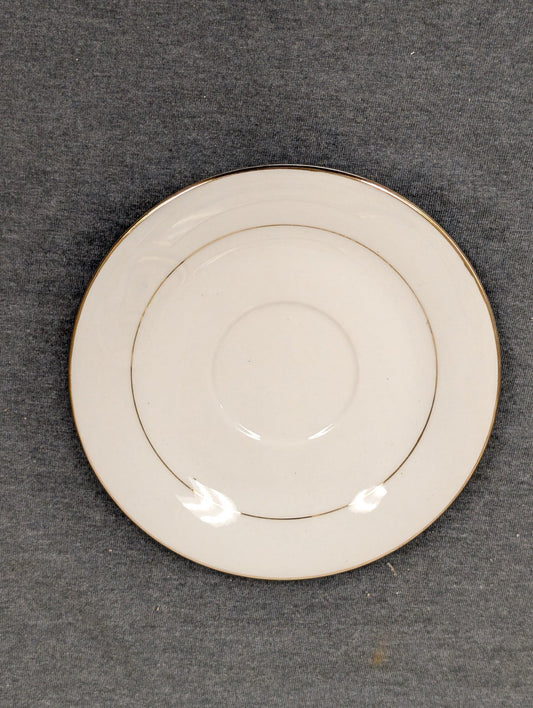 Front view of a small Sakura Classic Gold saucer plate with center indent.