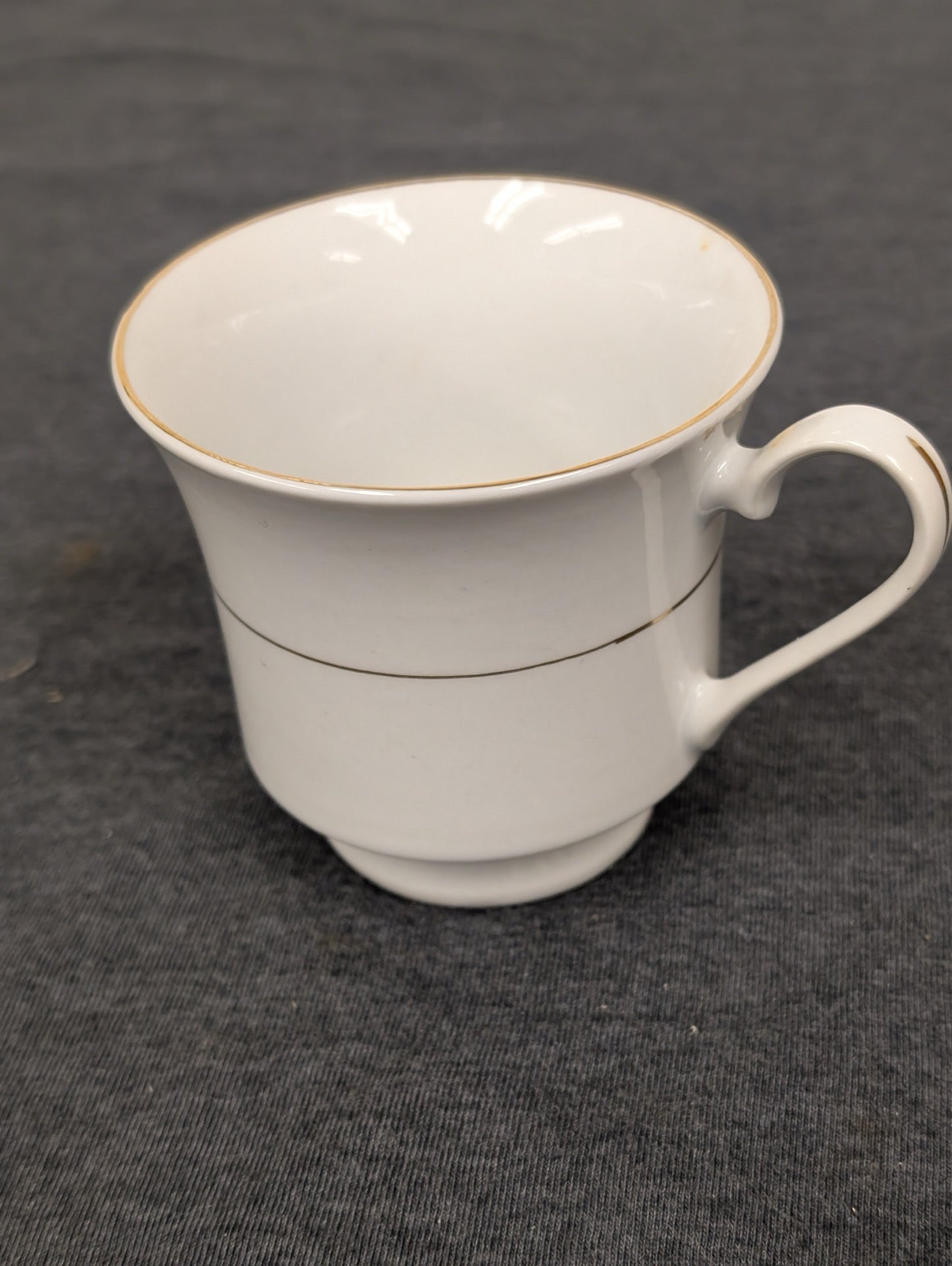 Side view of a white Sakura teacup with thin gold stripes