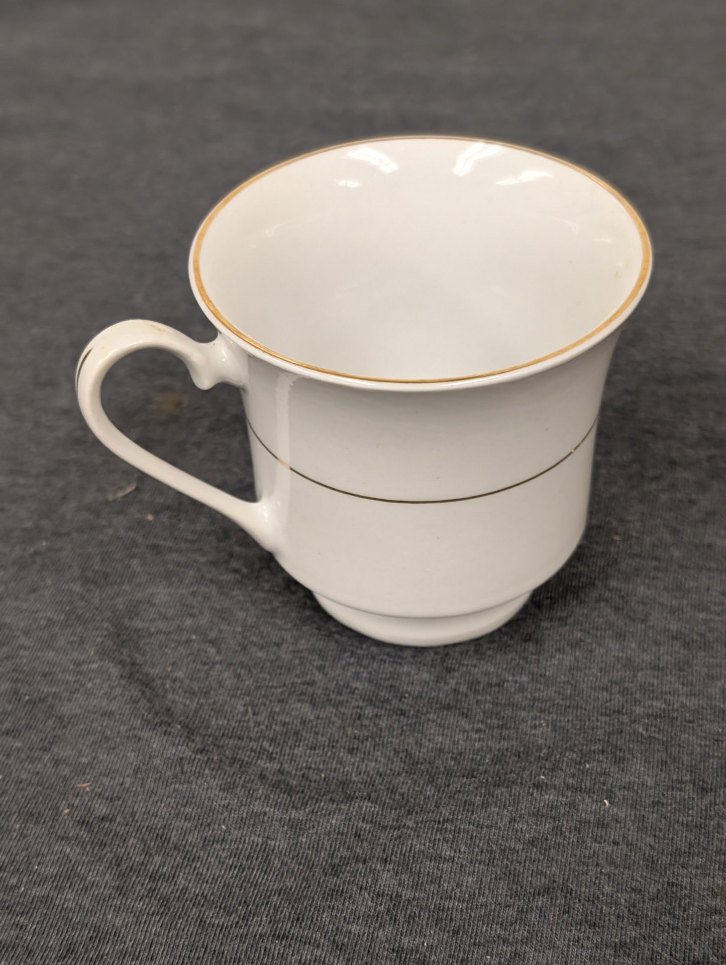 Side profile of a Sakura teacup featuring white china and gold bands