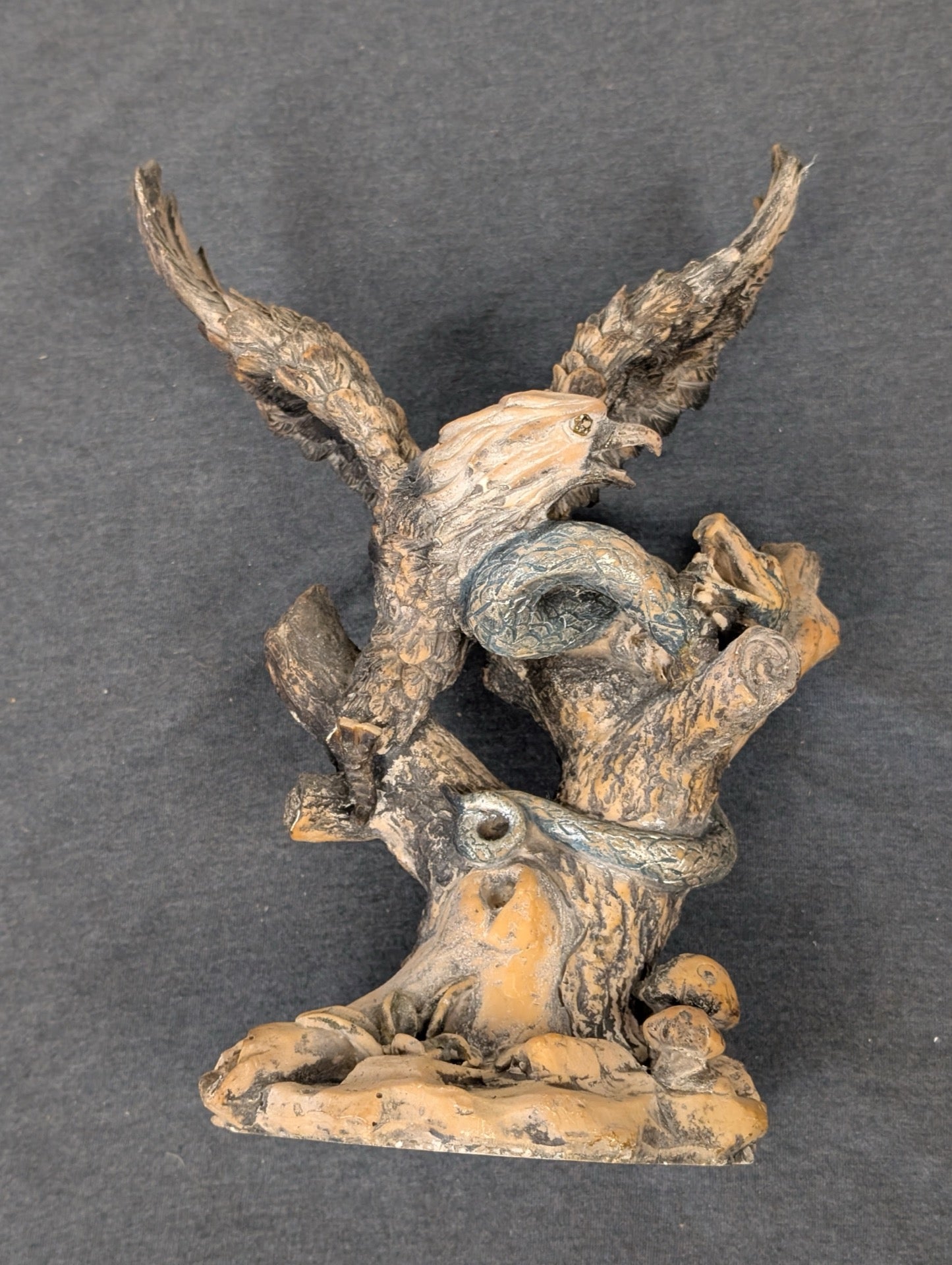 Resin sculpture of an eagle fighting a snake perched on a tree branch