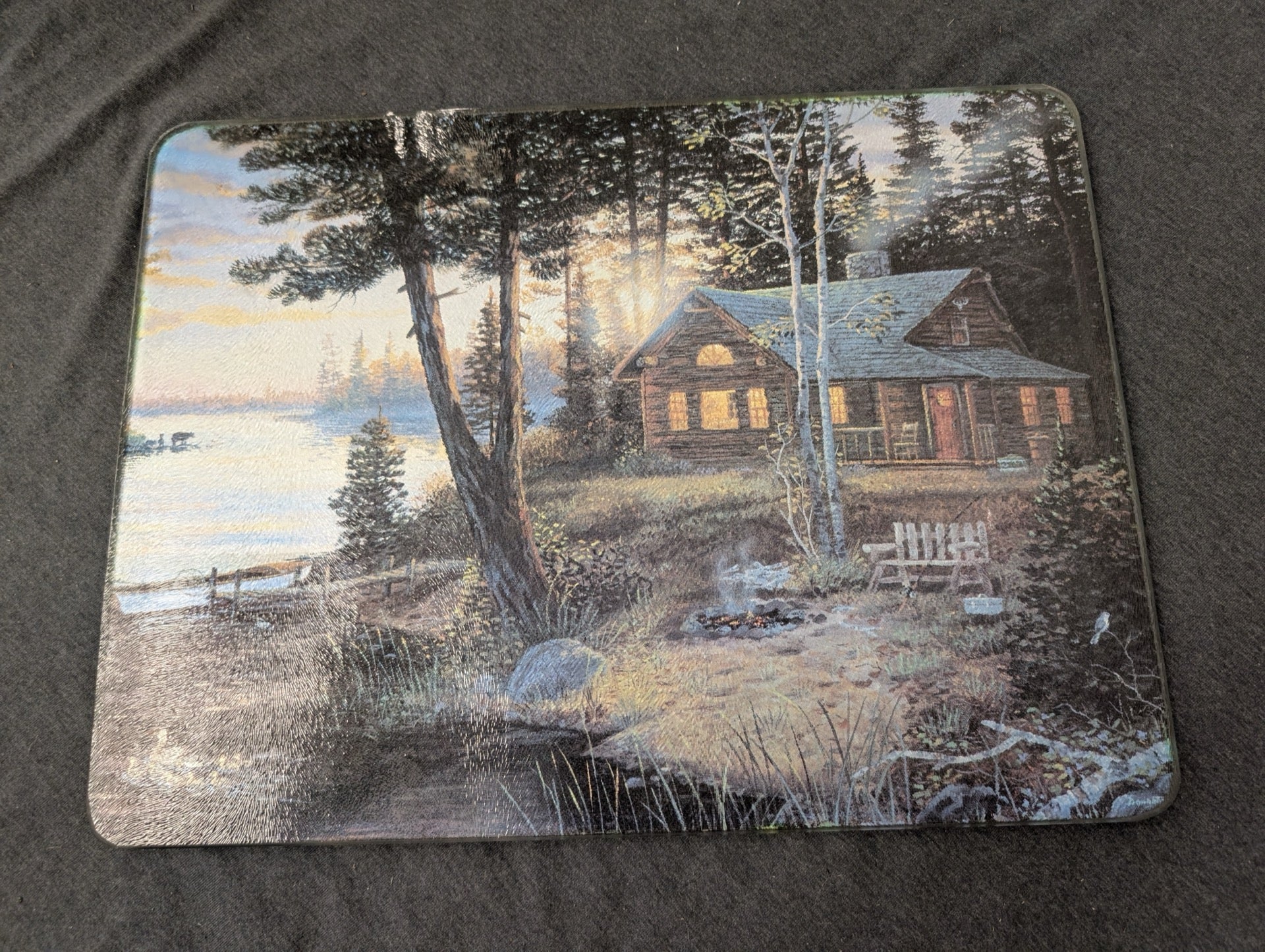 Tempered glass cutting board featuring an illustration of a log cabin by a lake at sunrise