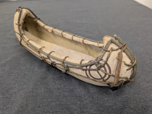 Small model canoe made of stretched material over a frame with string lacing