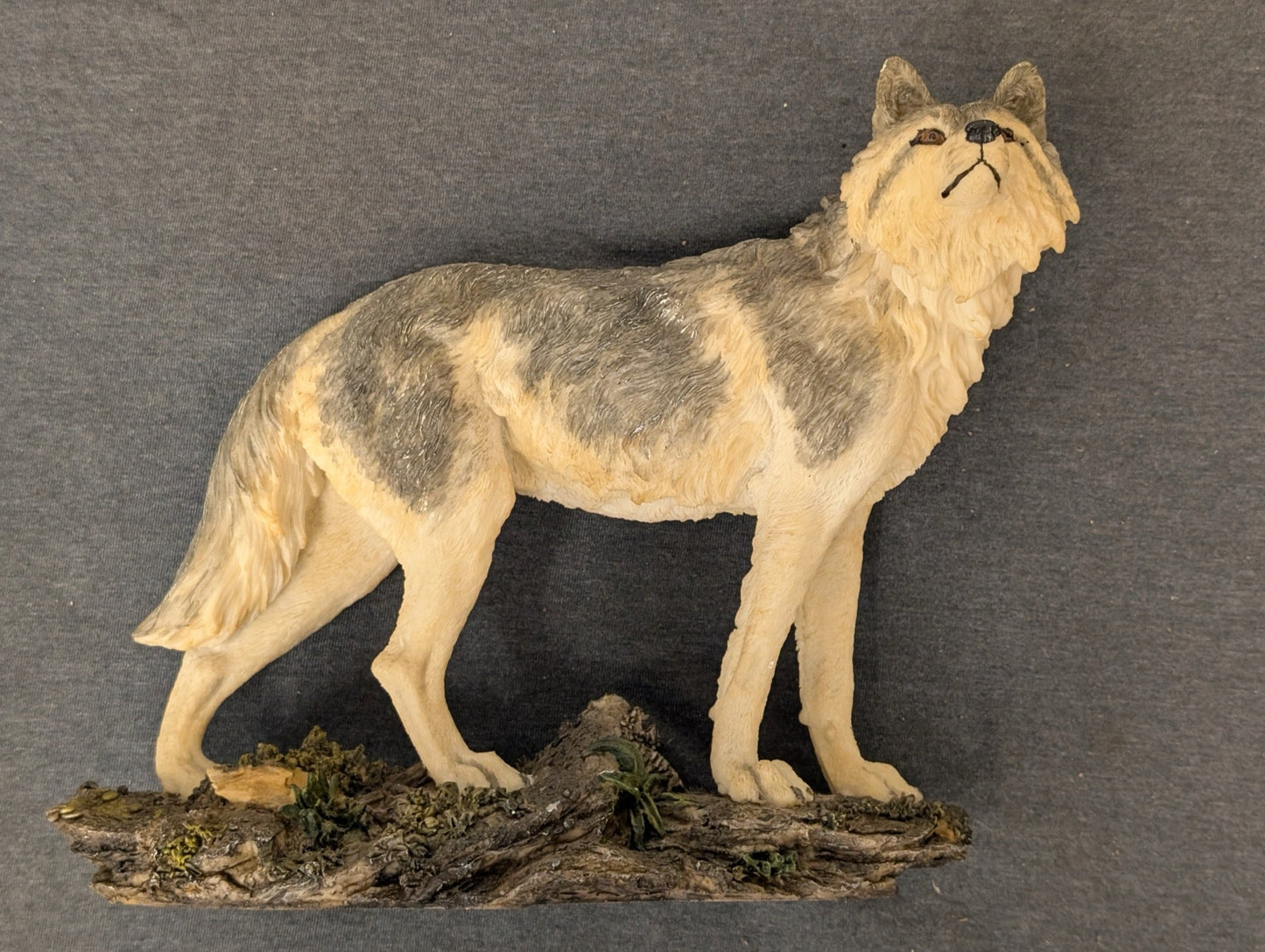 Detailed resin figurine of a grey and white wolf standing on a rocky base