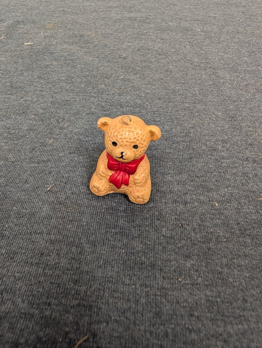 Tiny textured ceramic brown bear figurine with a red painted bow