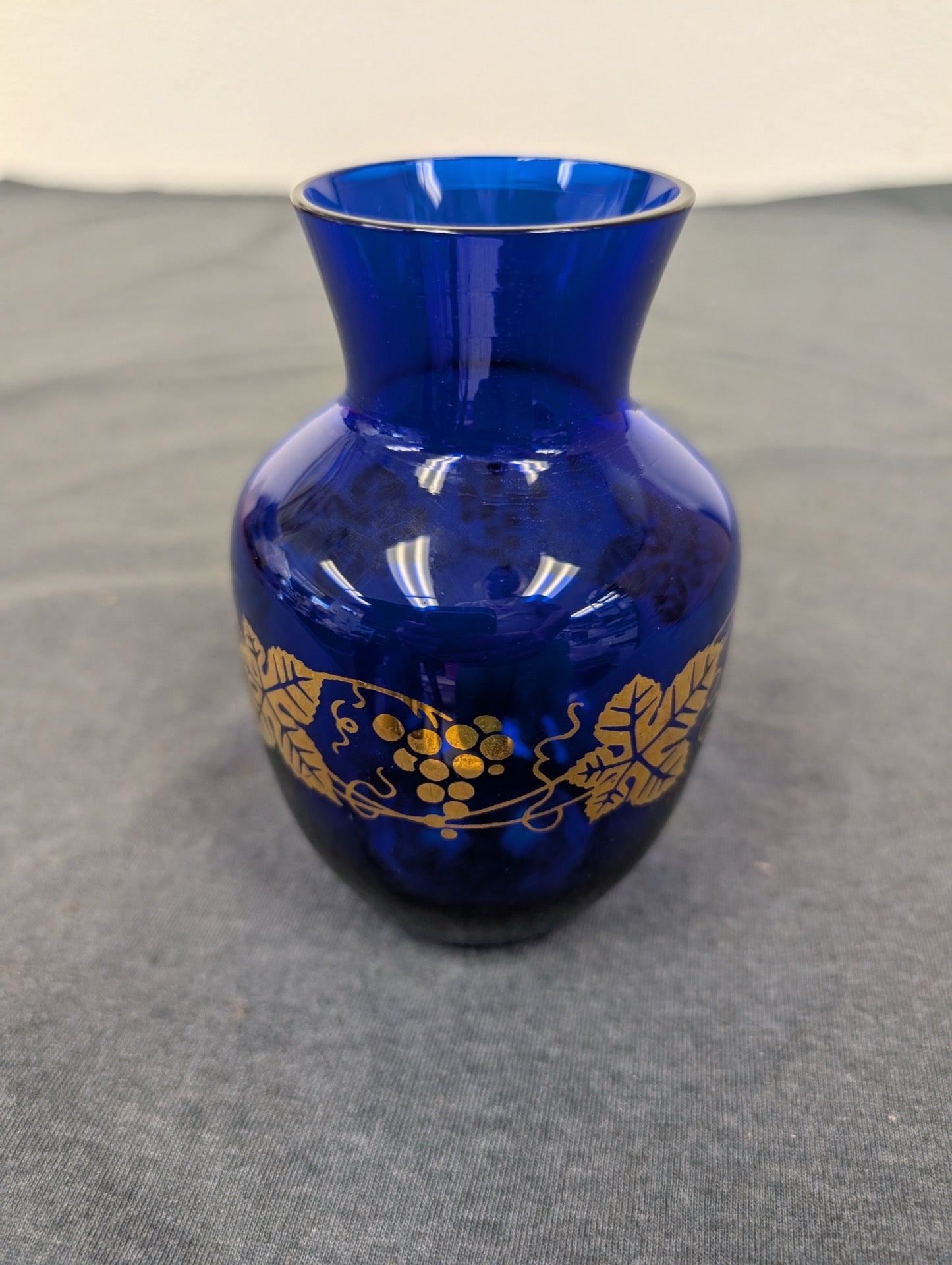 Small cobalt blue glass vase with a gold painted grape and vine design