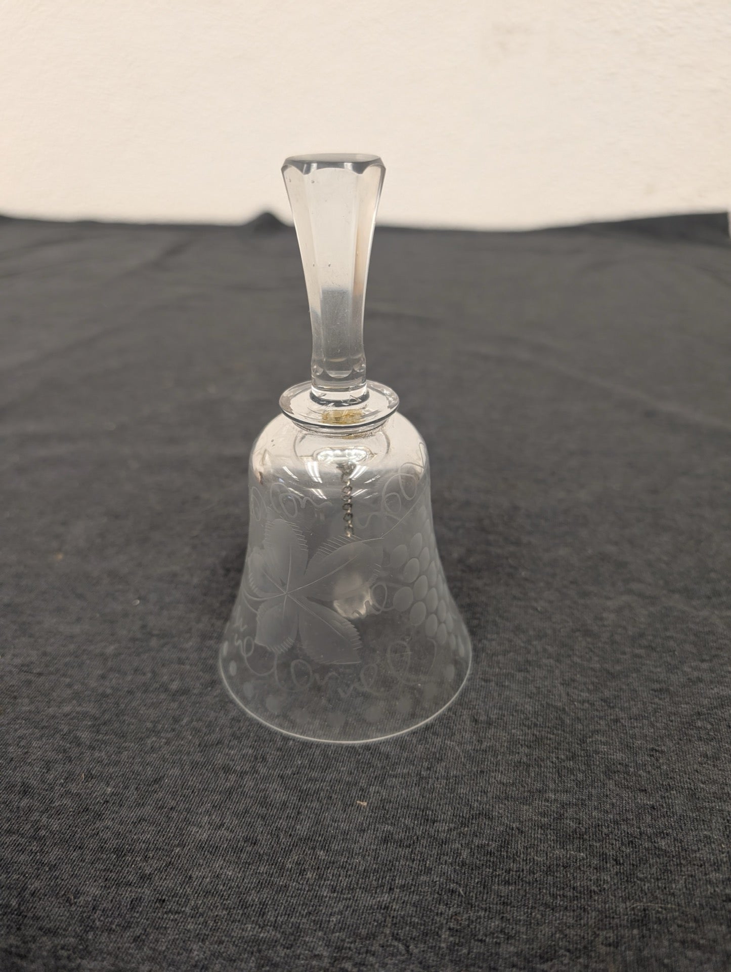 Clear glass bell with etched floral patterns and a long handle