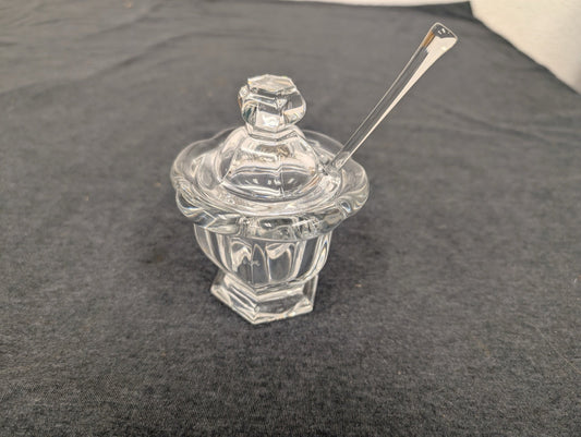 Clear Baccarat crystal jam pot with a matching faceted lid and a crystal spoon resting inside.