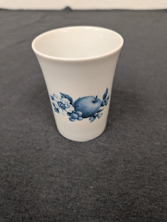Small white porcelain cup with a blue design of an apple, grapes, and flowers on the side.