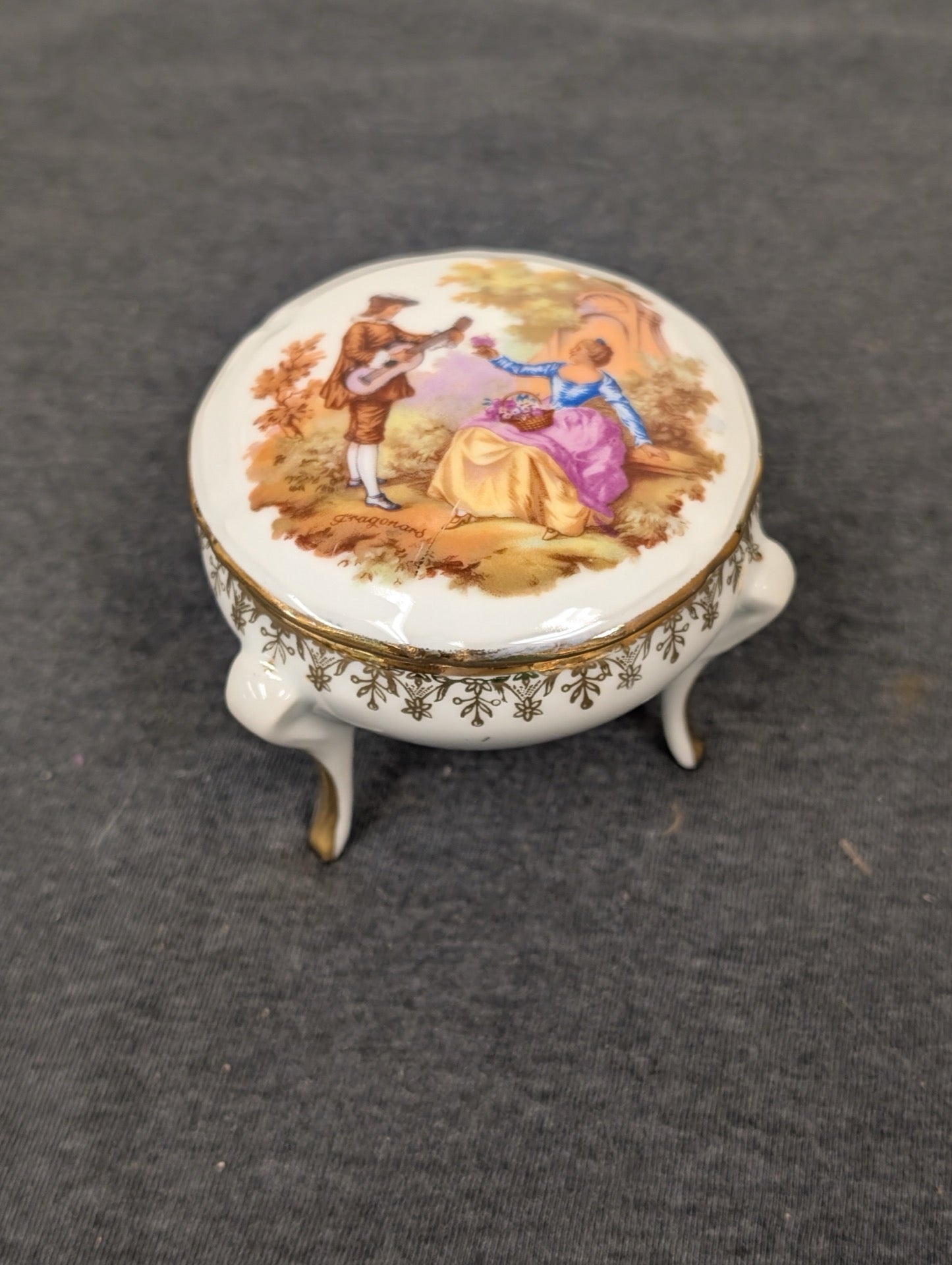 Closed Limoges footed trinket box with a Fragonard courting couple painted on the lid.