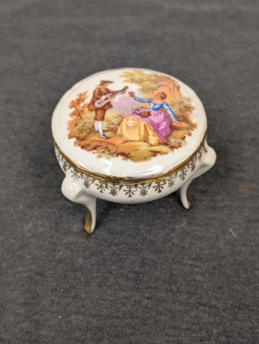 Closed Limoges footed trinket box with a Fragonard courting couple painted on the lid.