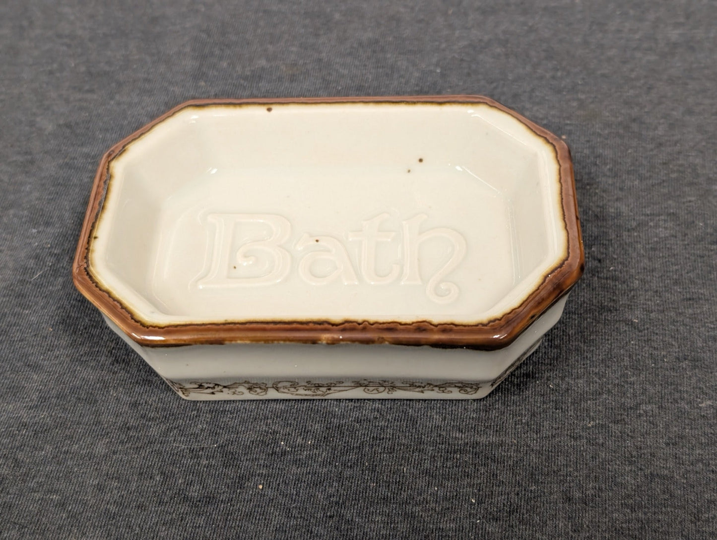 Rectangular vintage ceramic soap dish with the word Bath embossed inside and brown trim.