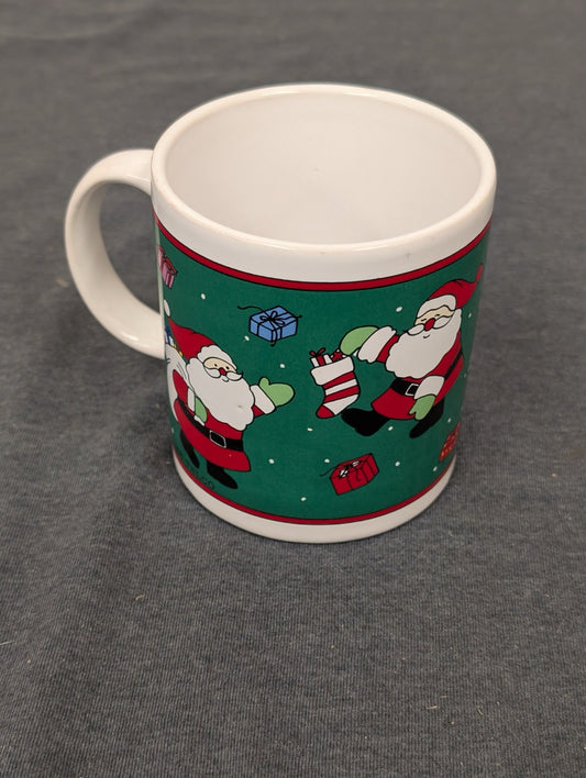 Ceramic coffee mug featuring a green background with Santa Claus and presents.