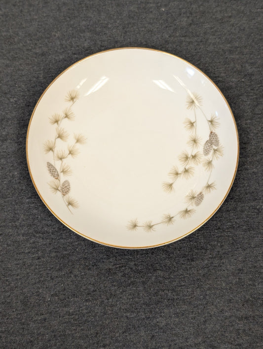 Full front view of the white plate with pinecone and pine needle motif.