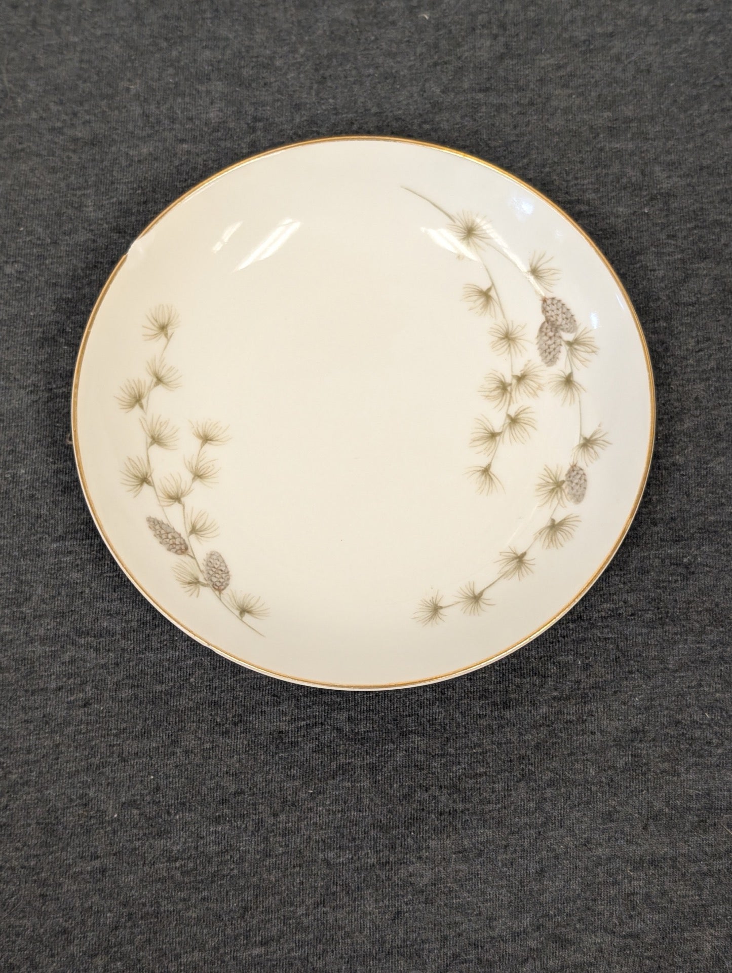 Front view of a Mikasa Sequoia plate displaying pine needles and gold trim