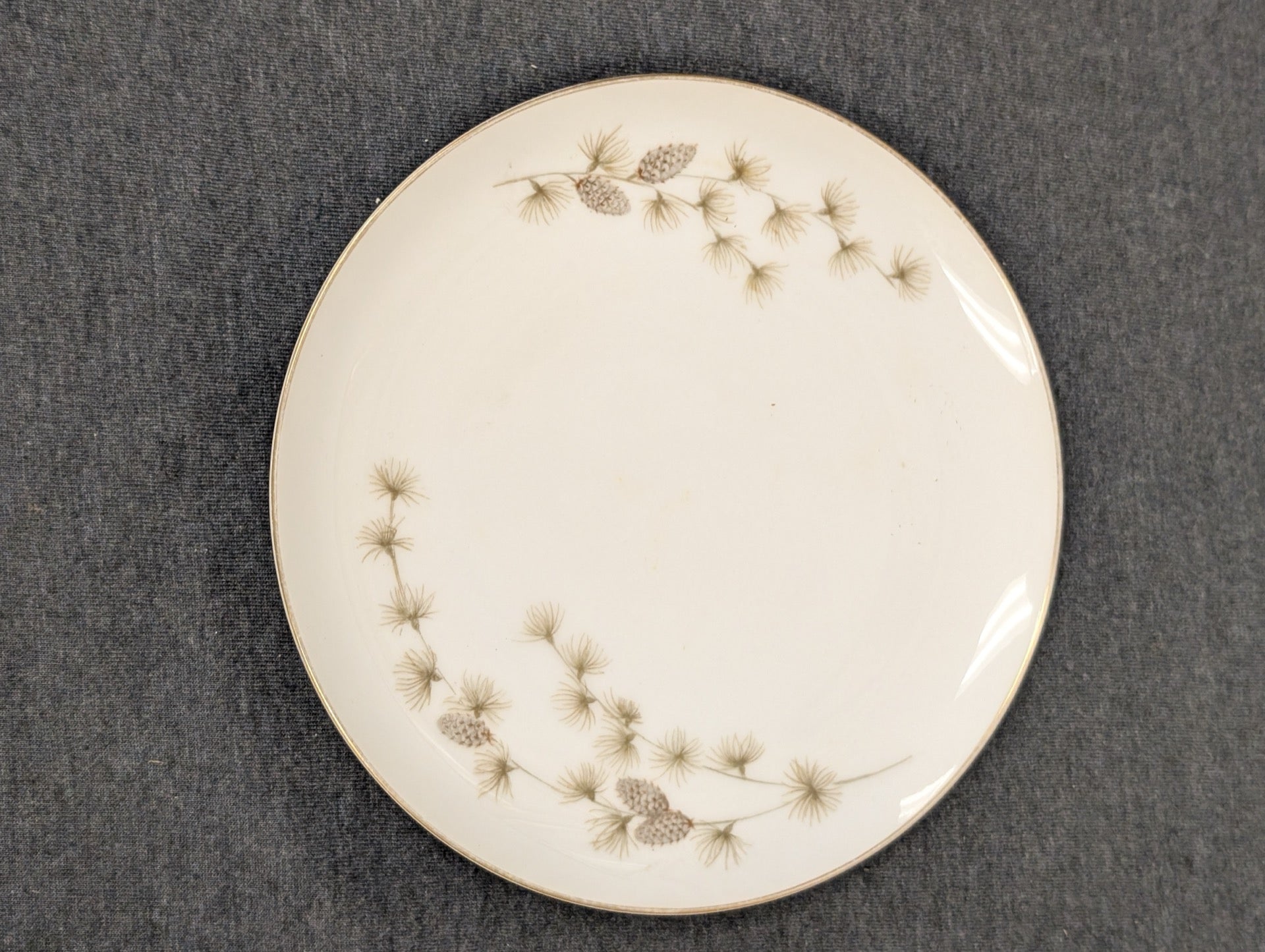 Vintage Mikasa plate with pinecone and pine needle design with gold rim.