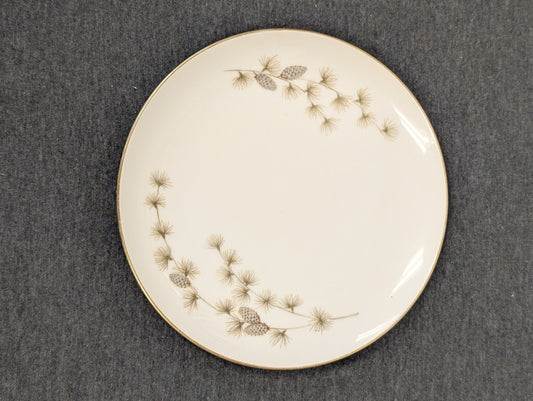 White vintage dinner plate featuring a pinecone and pine needle border design.