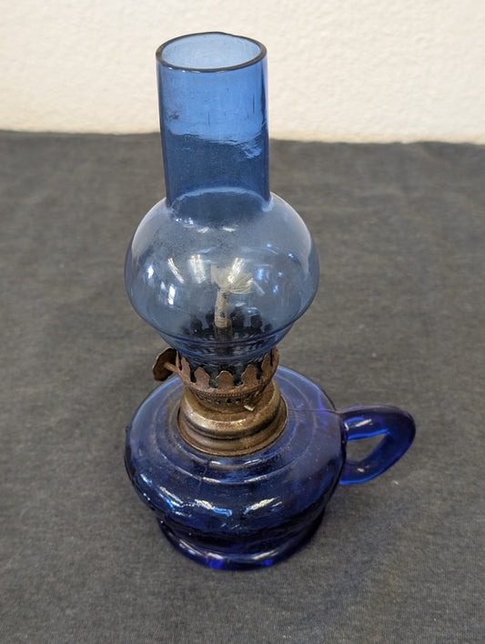 Miniature blue glass vintage oil lamp on a dark surface