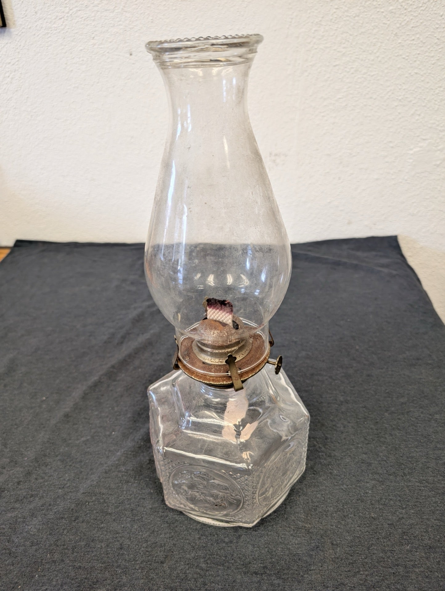 Clear glass oil lamp with a tall glass chimney on a dark table