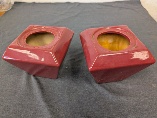 Two red ceramic square holders with a tapered shape and circular top opening
