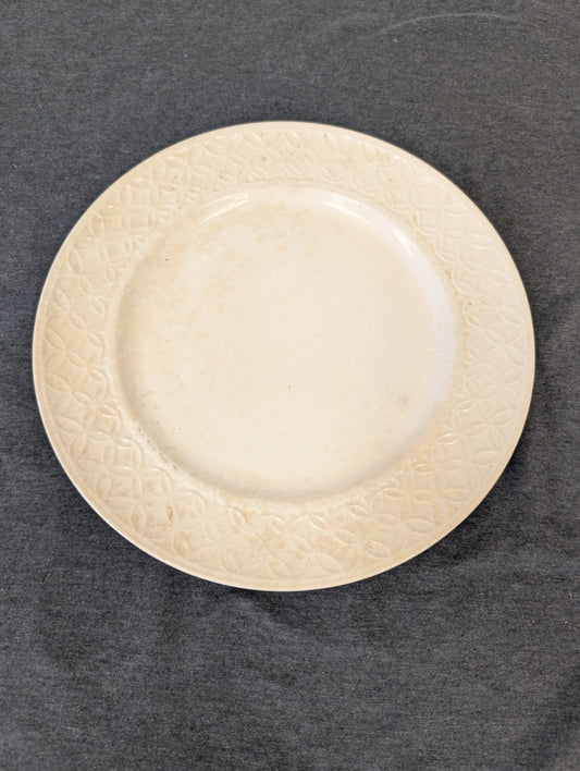 Cream plate with an embossed geometric circular pattern around the rim.