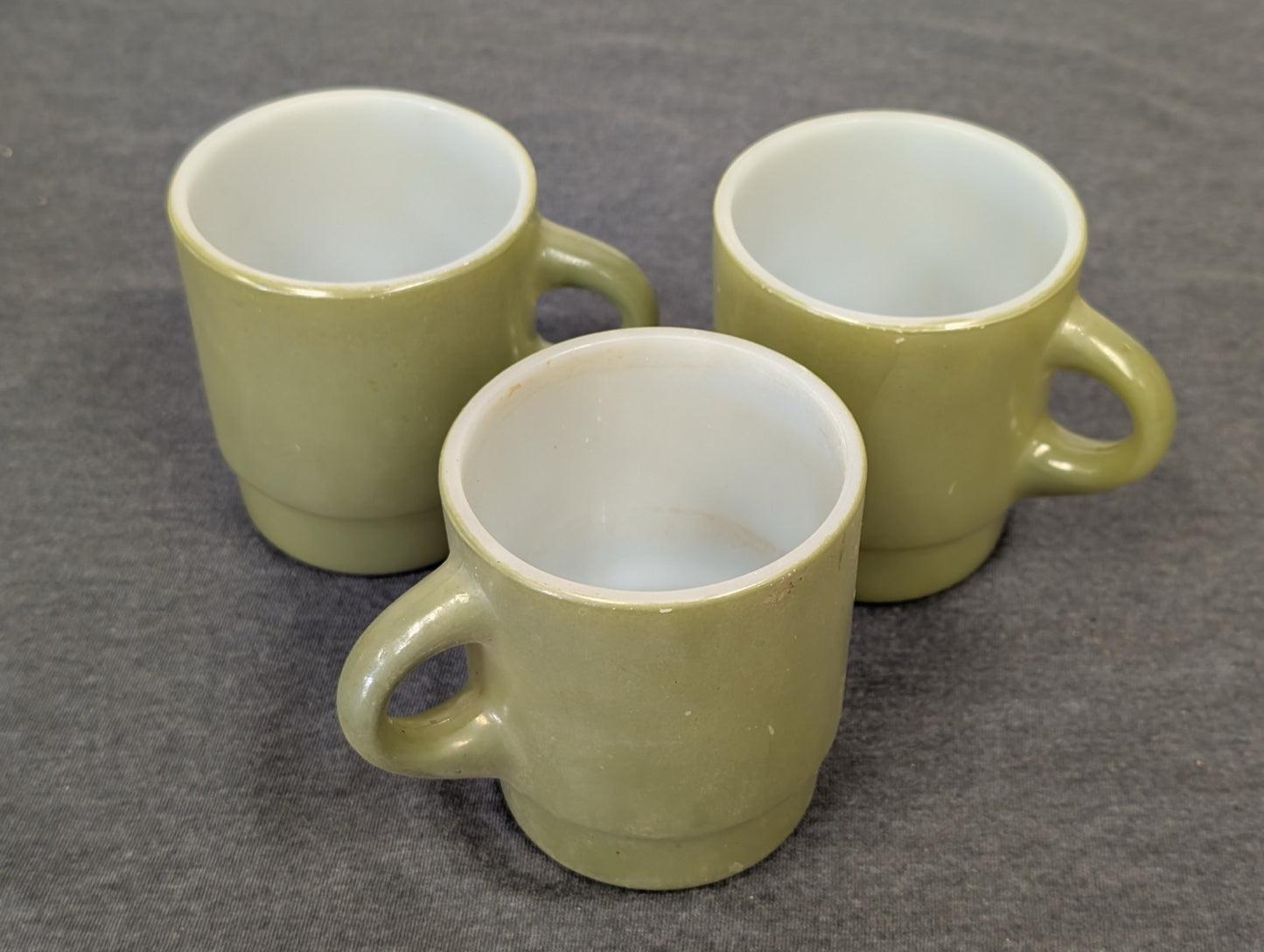 Three avocado green milk glass mugs in a stacking style