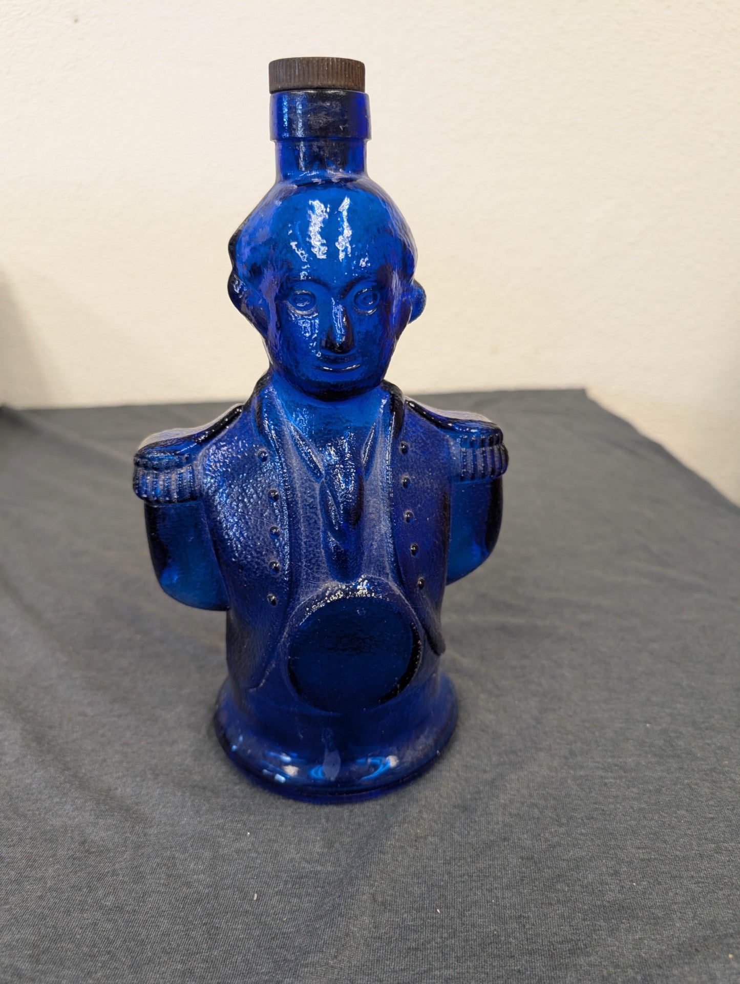 Cobalt blue glass liquor bottle in the shape of a bust.