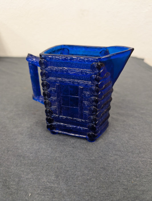 Cobalt blue glass creamer pitcher shaped like a log cabin.