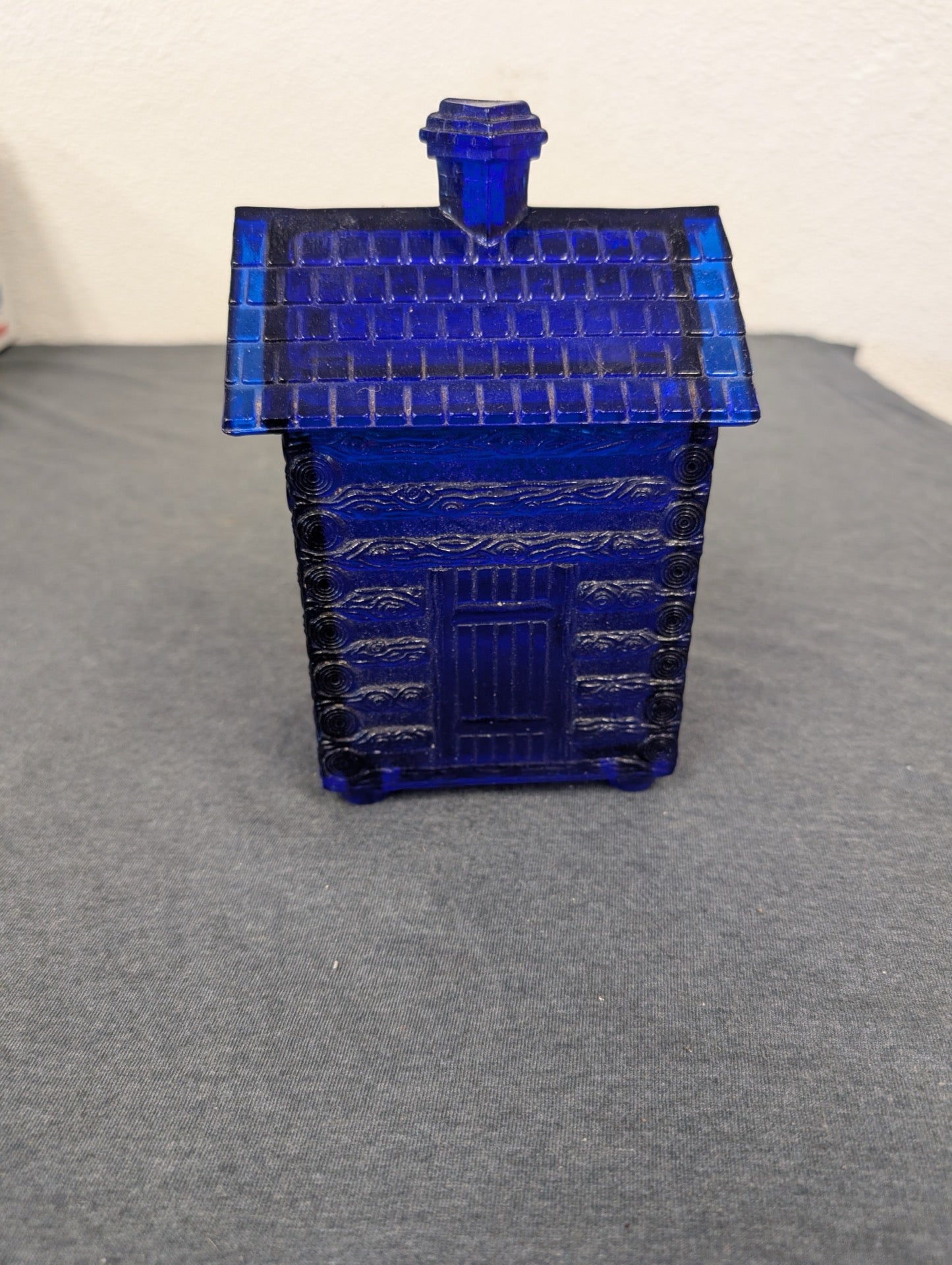 Cobalt blue glass container shaped like a log cabin.