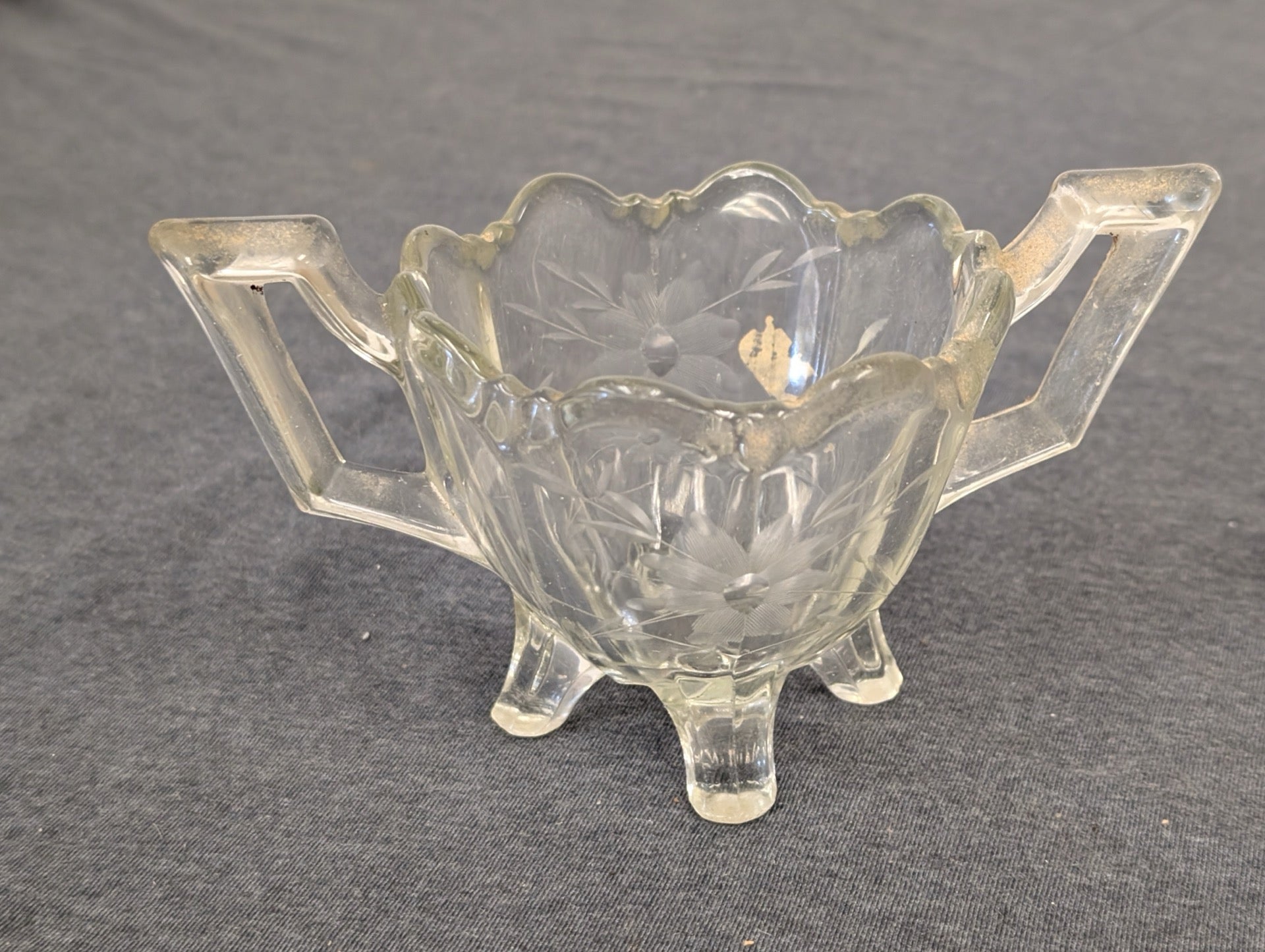Clear glass footed sugar bowl with handles and floral etching.