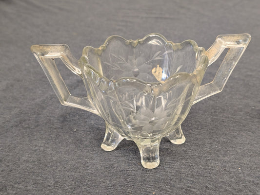 Clear glass footed sugar bowl with handles and floral etching.