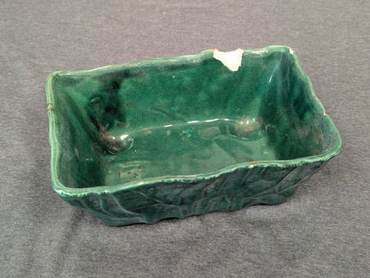 Green rectangular ceramic planter with leaf pattern and a large broken chip on the rim.