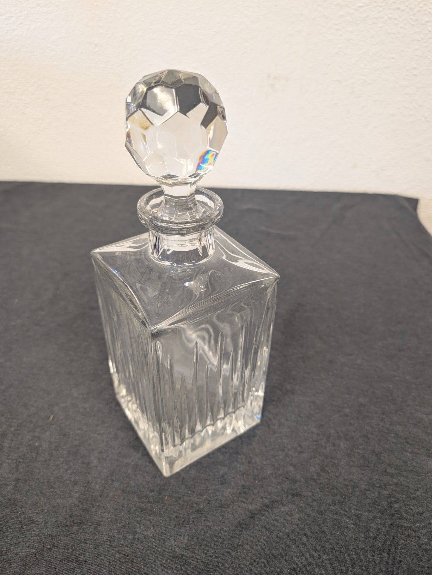 Fully assembled ribbed clear glass liquor decanter with faceted stopper.