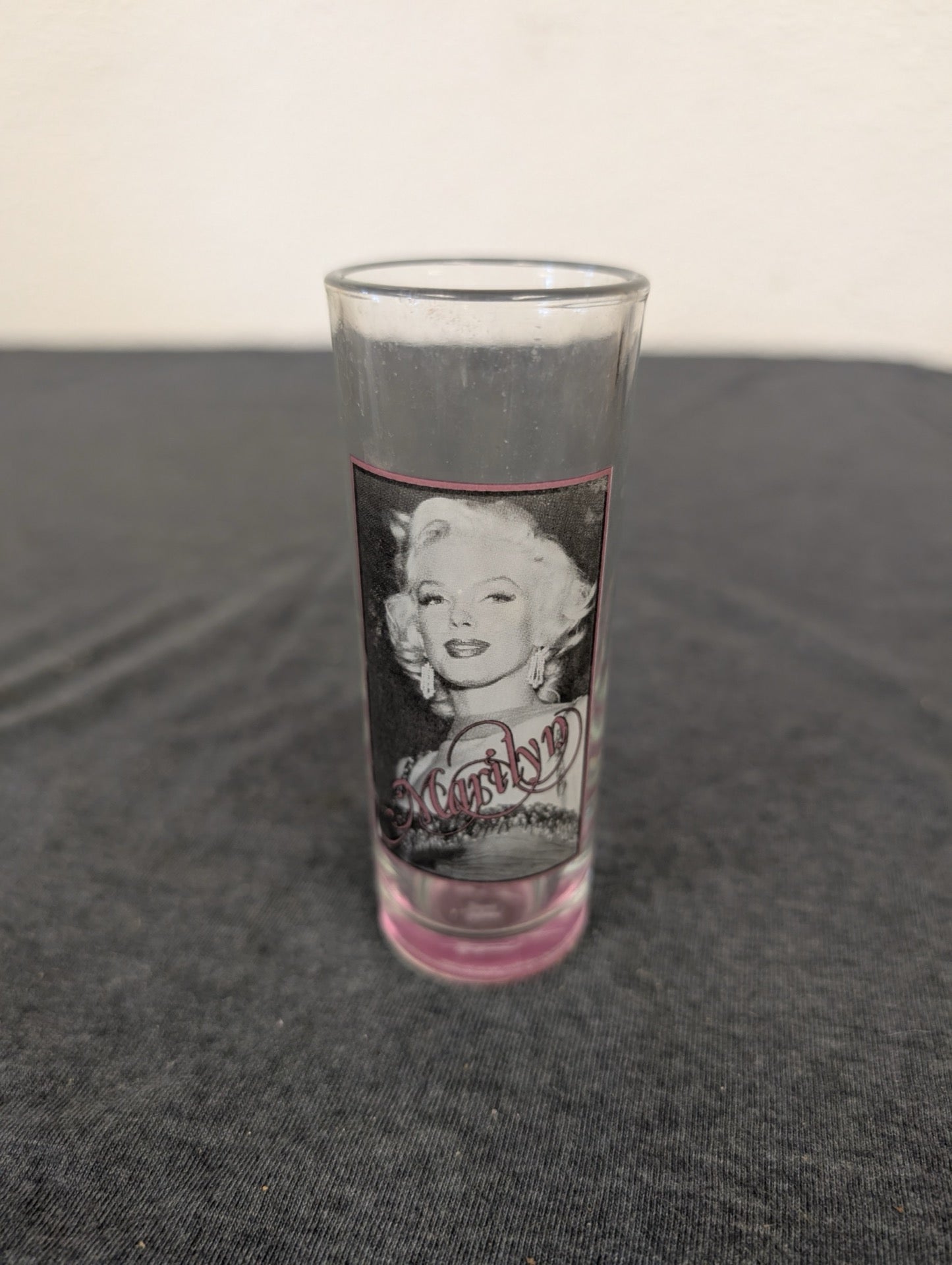 Clear tall shot glass featuring Marilyn Monroe with a pink tinted base.