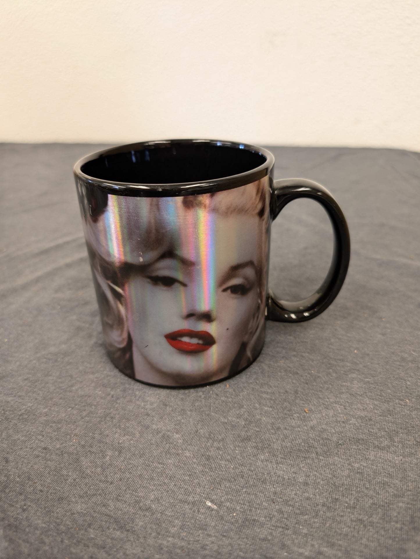 Black coffee mug with a holographic iridescent Marilyn Monroe face.