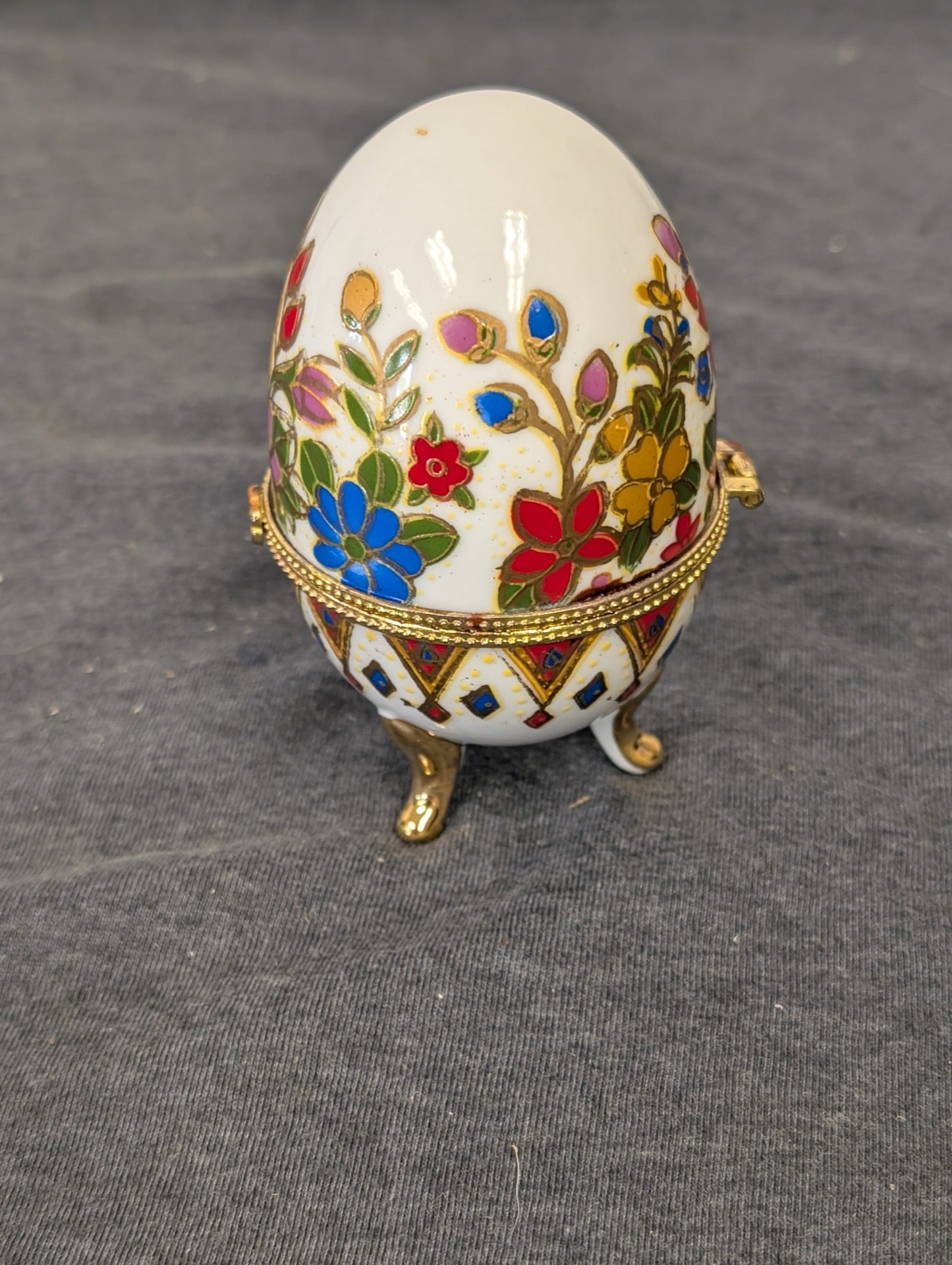 Closed enamel egg trinket box with vibrant flowers on gold feet
