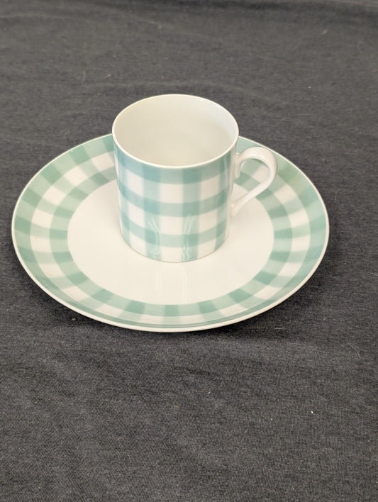 Teal and white gingham checkered teacup resting on a matching saucer.