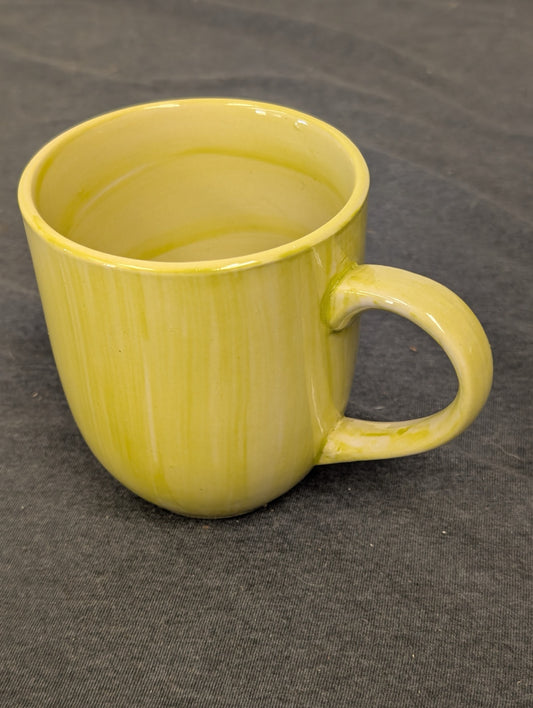 Yellow ceramic coffee mug with a vertical drip glaze effect on a dark background.