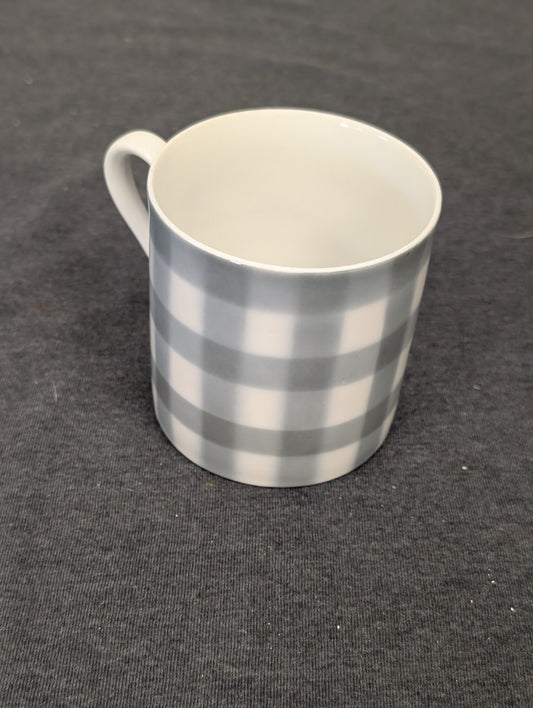 White ceramic coffee mug with a grey gingham checkered pattern on the outside.