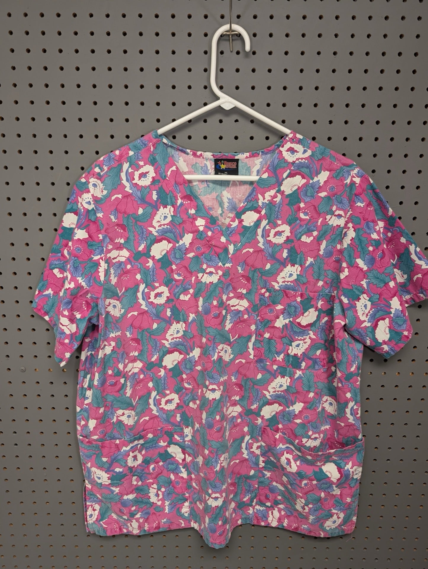 Front view of Brisco Apparel pink and teal floral scrub top