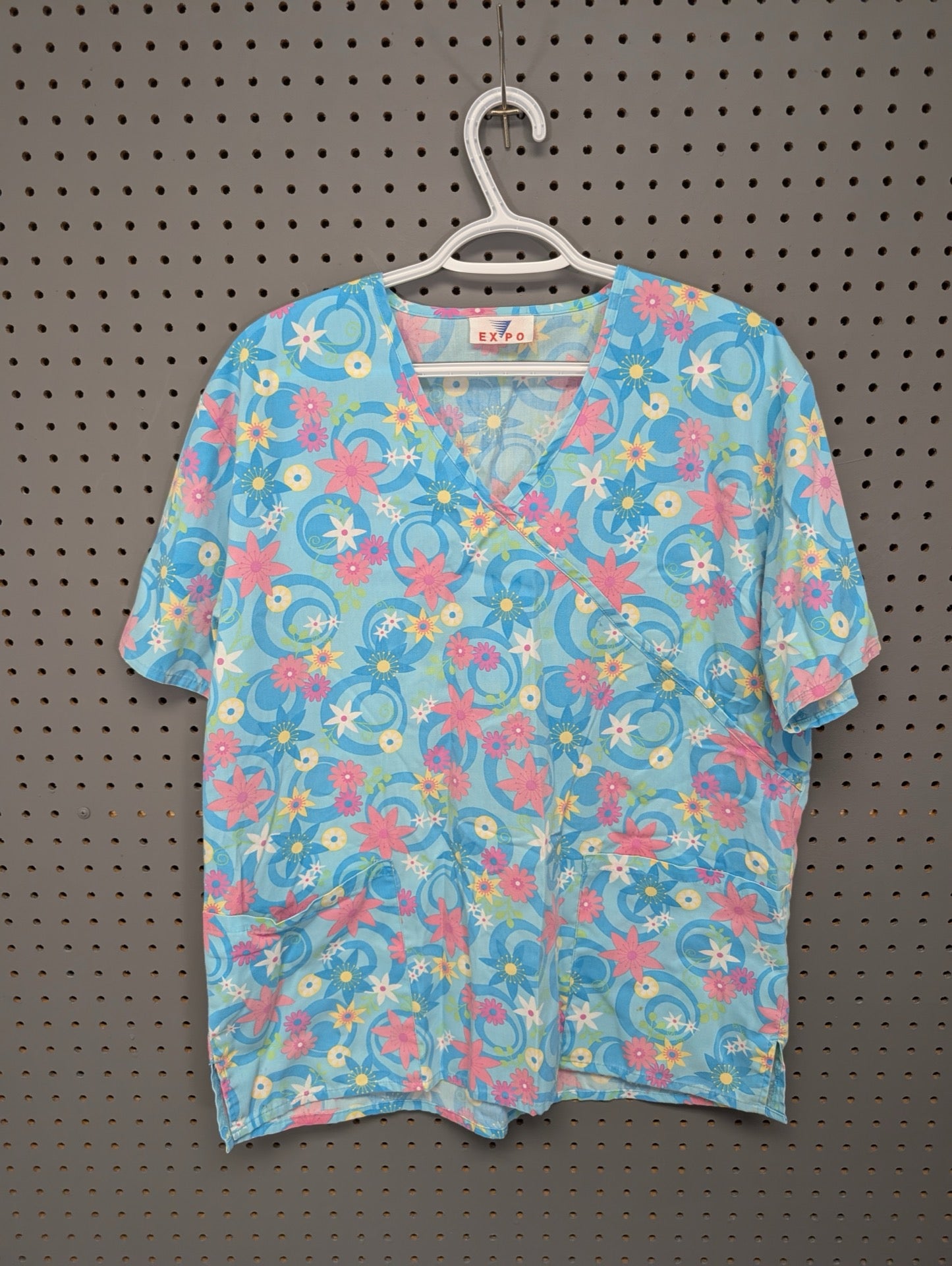 Front view of EXPO blue geometric faux wrap scrub top