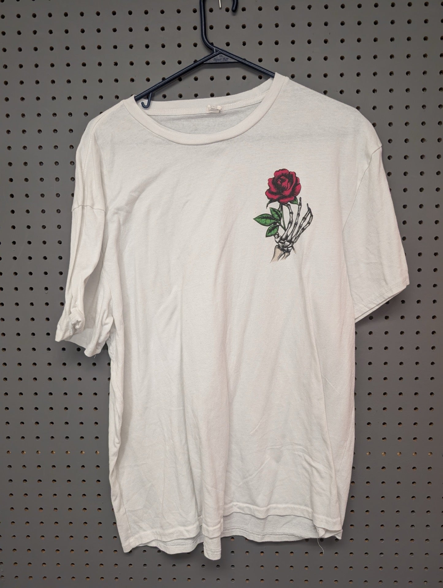 Front view of white t-shirt with skeleton hand and rose graphic
